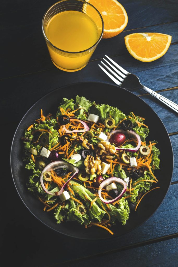 Large colorful salad with vegetables and seeds in a dark bowl