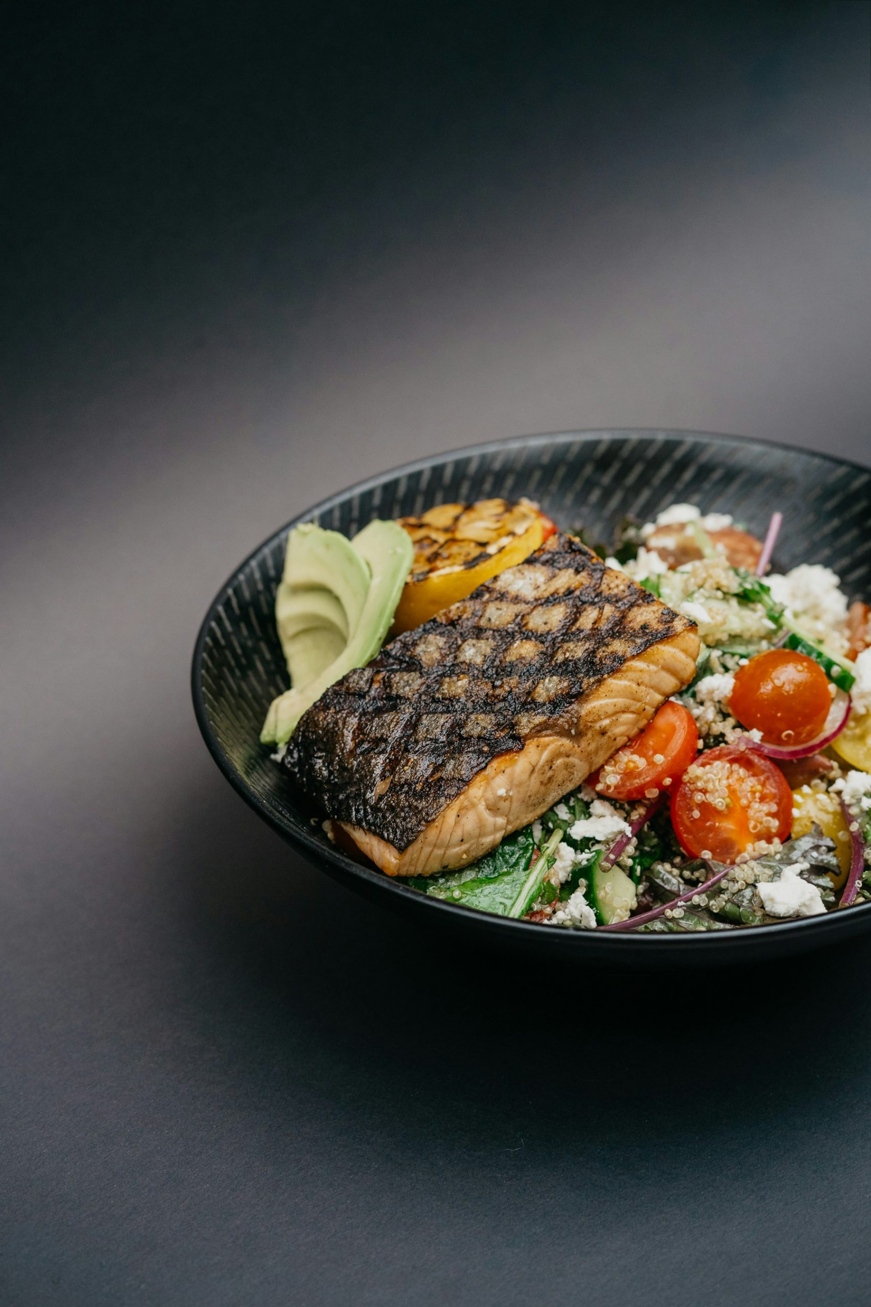 Grilled salmon bowl with tomatoes, avocado and grains