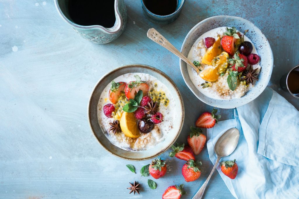 Breakfast bowls with fruit and oats on a light blue table