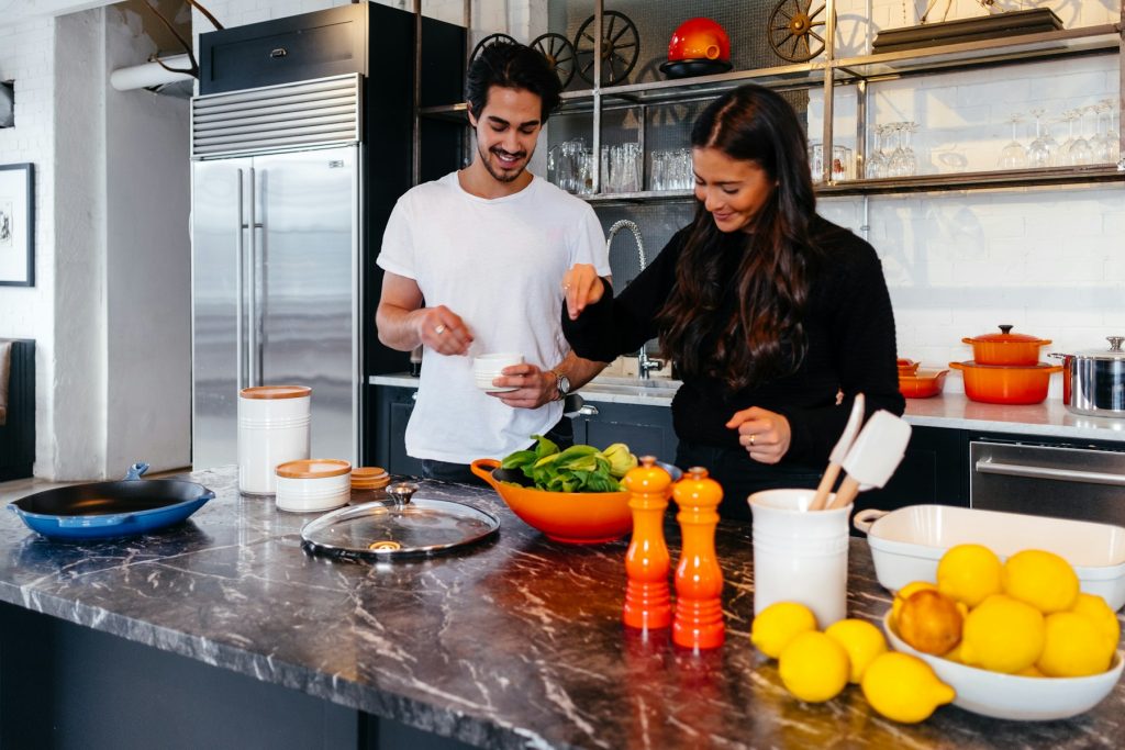 Couple preparing a healthy meal with fresh vegetables and lemons
