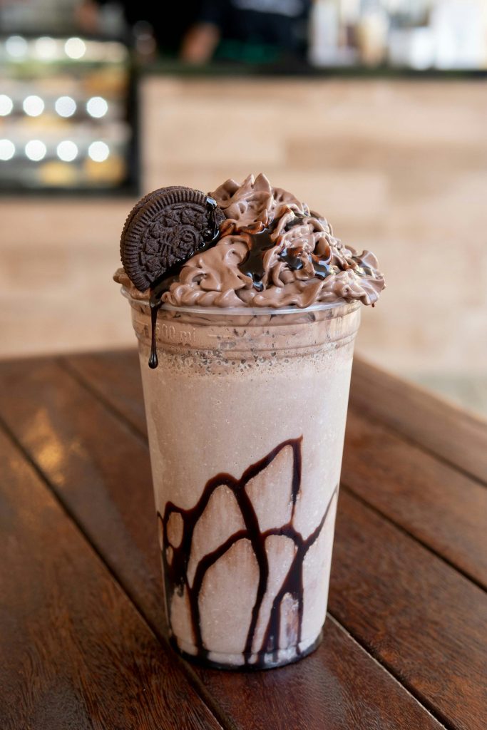 Thick chocolate shake in a glass on a wooden table