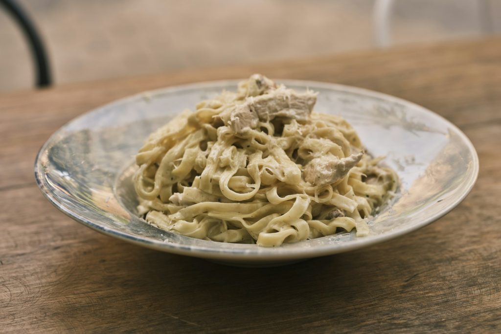 A bowl of creamy chicken fettuccine on a wooden table