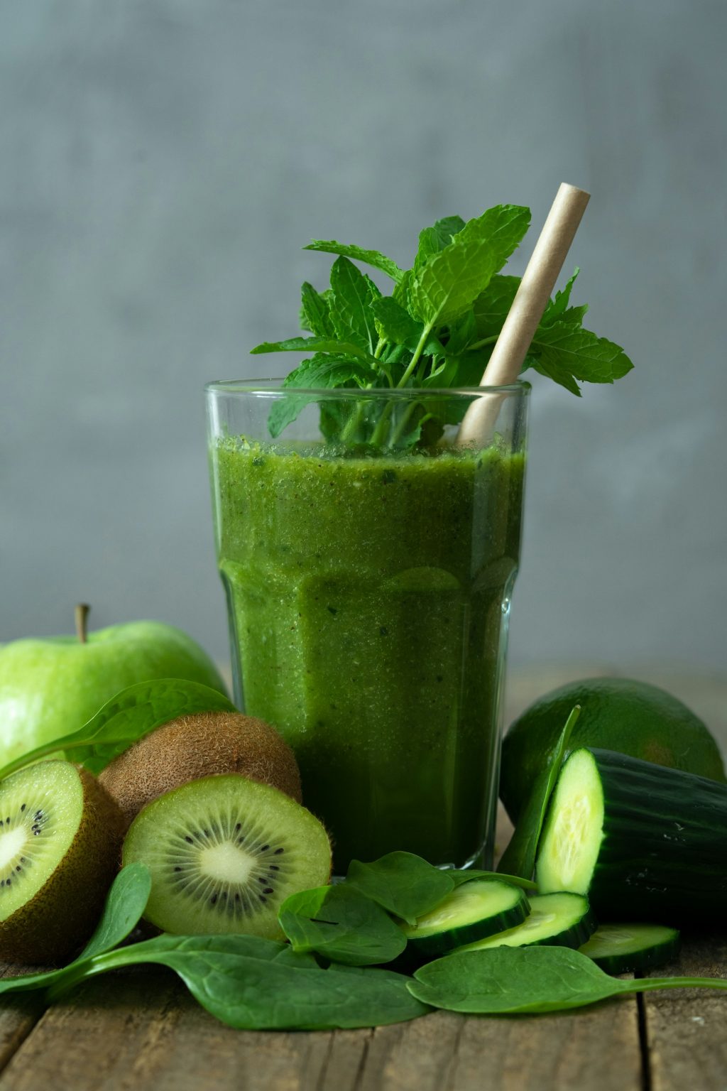 Green smoothie in a tall glass with fresh fruit