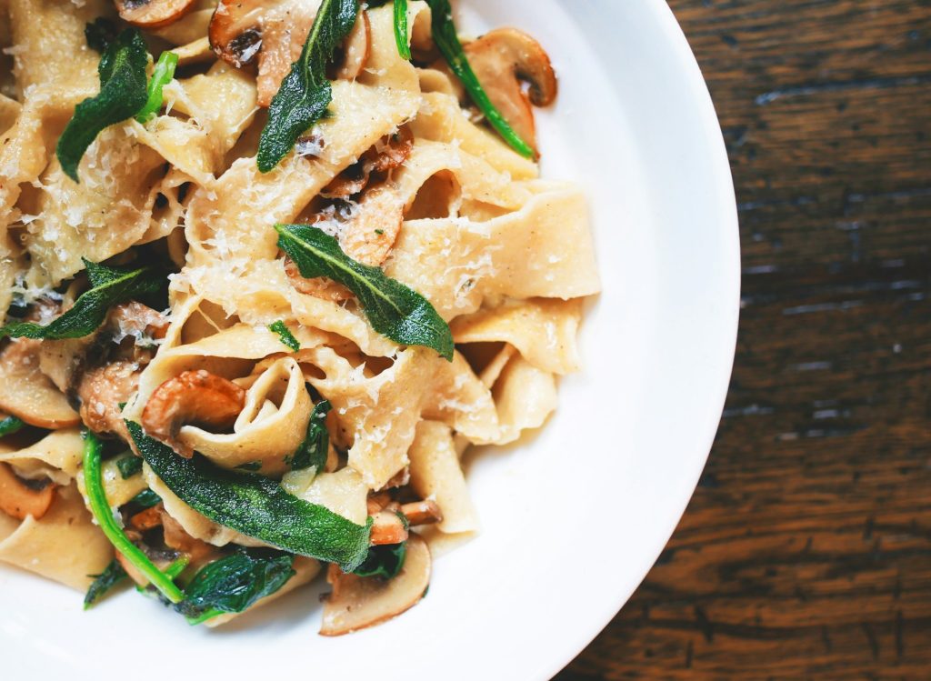Pasta with greens and parmesan on a white plate