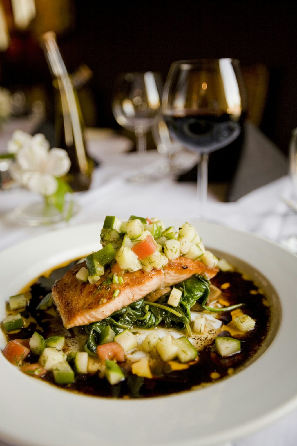 Baked salmon fillet topped with fresh salsa on a white plate